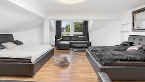 Ein modernes Schlafzimmer mit einem großen Bett, einer Couch, einem kleinen Tisch und Blick ins Freie.