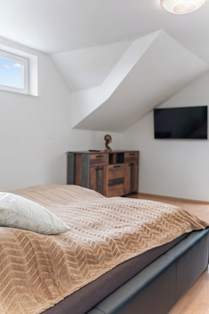 A bedroom with a bed, a dresser, and a TV mounted on the wall. - Black Dragon Castle (Prague 20)