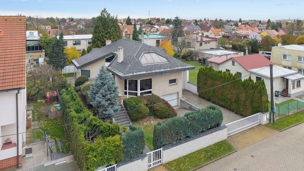 Ein Wohngebiet mit einem modernen Haus, das ein geneigtes Dach, große Fenster und einen gepflegten Garten aufweist.