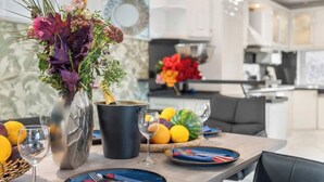 Ein stilvoller Essbereich mit Tisch für Zwei, einer Blumenvase und einer Obstschale.