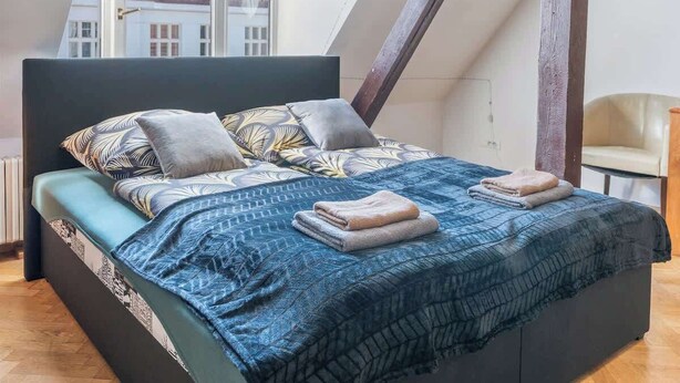 Un dormitorio con techo curvo, cama con ropa de cama estampada y vistas a edificios.