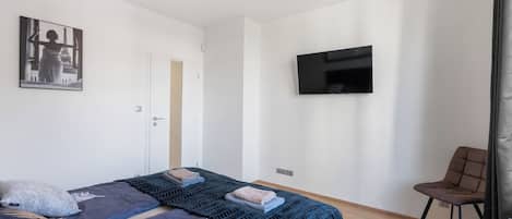 Un dormitorio con una cama, un televisor y una silla.