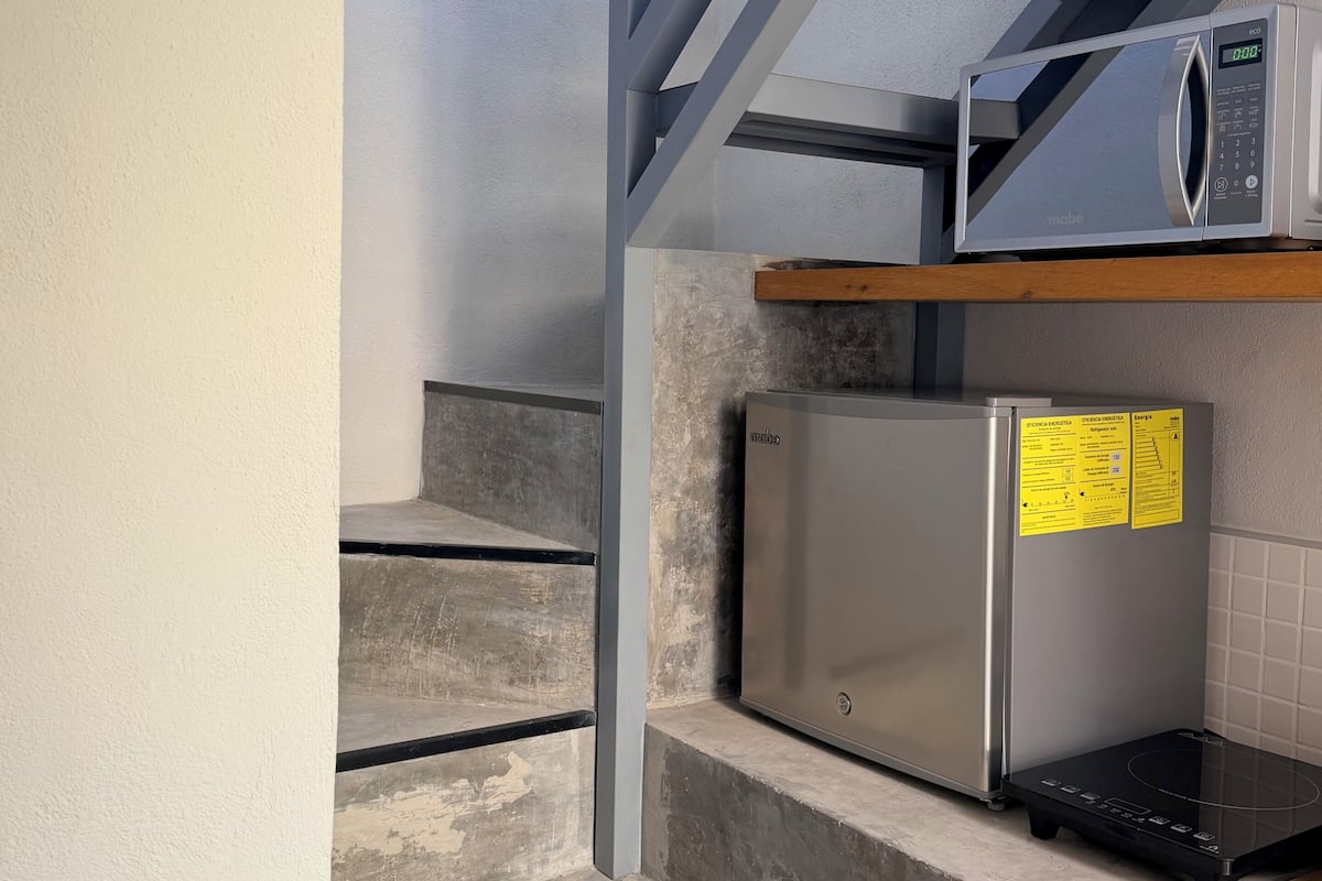Una cocina con microondas, refrigerador de acero inoxidable y encimera de madera.