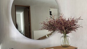 Uno specchio su un consolle in legno, un vaso con fiori secchi e un quadro incorniciato.
