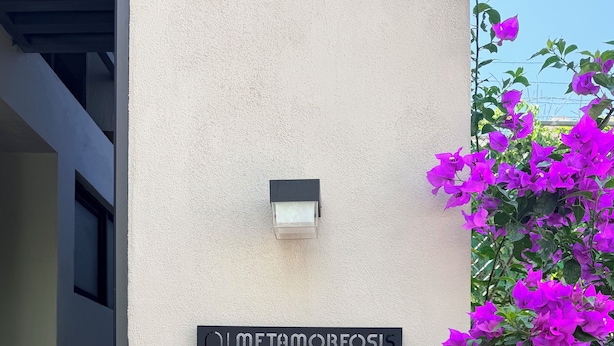 Ingresso di un edificio con un cartello che riporta 'METAMORFOSIS' e un lampadario a parete.