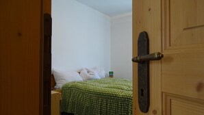 Una stanza con un letto, una porta in legno e un comodino.