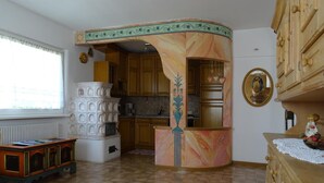 Una cucina con mobili in legno, una colonna in marmo, un termosifone e un piccolo tavolo con un oggetto decorativo.