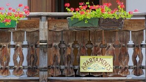 Un recinto in legno con un cartello che riporta la scritta 'APARTMENTS' e fioriere con fiori rossi.