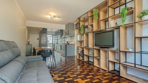 Ein modernes Wohnzimmer mit einer Couch, einem Essbereich und einer Küche im Hintergrund.