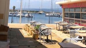 Terraza con asientos al aire libre con vista a un puerto deportivo y barcos.