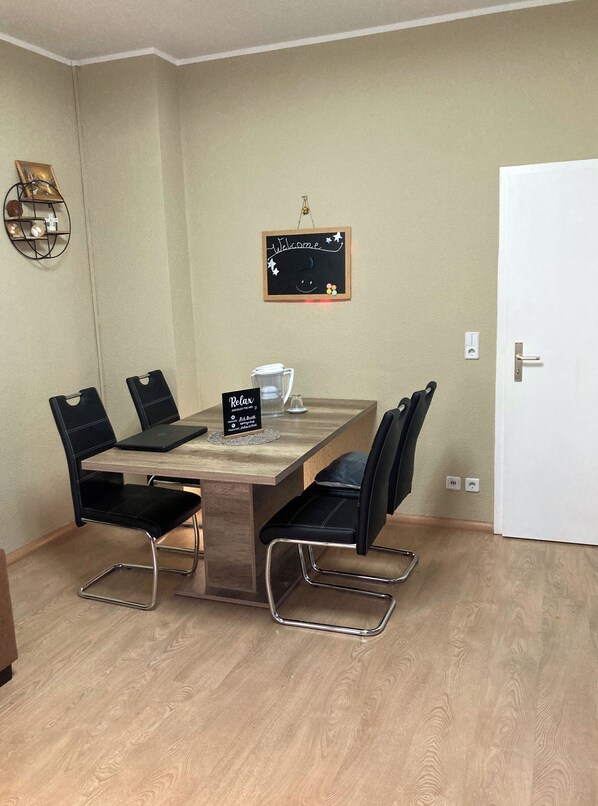 Een eethoek met een houten tafel, zwarte stoelen en een bordje met de tekst 'Relax'.