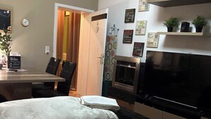 Ein Schlafzimmer mit zwei Betten, einem Fernseher und einer kleinen Küchenzeile.