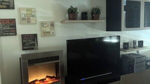 Ein modernes Wohnzimmer mit integriertem Kamin, einem Flachbildfernseher und Holzboden.