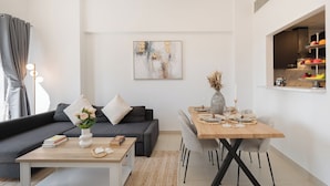 En moderne stue med sofa, sofabord og spisebord dækket til et måltid.
