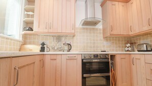 Una cocina moderna con armarios de madera, horno empotrado y cafetera.