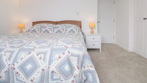 Un dormitorio con cama, dos lámparas de noche, una mesita de noche, un ventilador de techo y una puerta.
