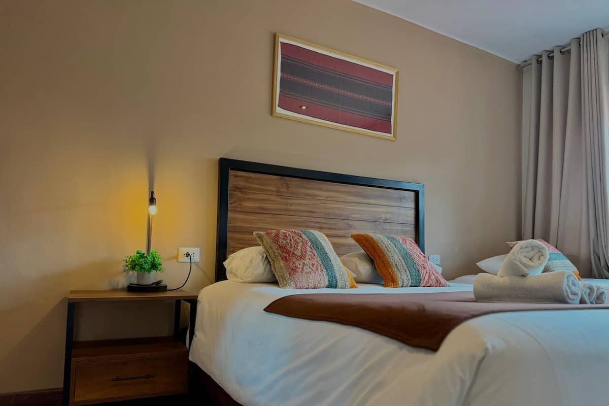 Ein Hotelzimmer mit Bett, Nachttisch mit Lampe, einer kleinen Pflanze und einem Wandbild.