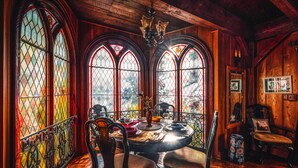 A dining area with a round table, chairs, and stained glass windows.