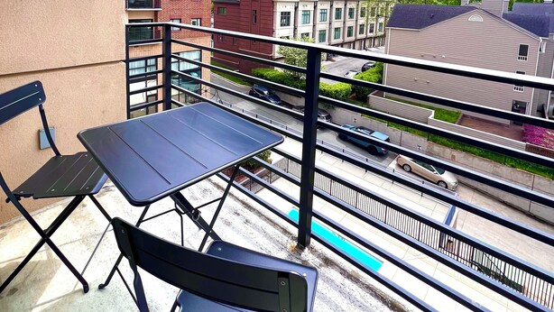 Ein Balkon mit Tisch und Stühlen mit Blick auf eine Skyline mit Hochhäusern.