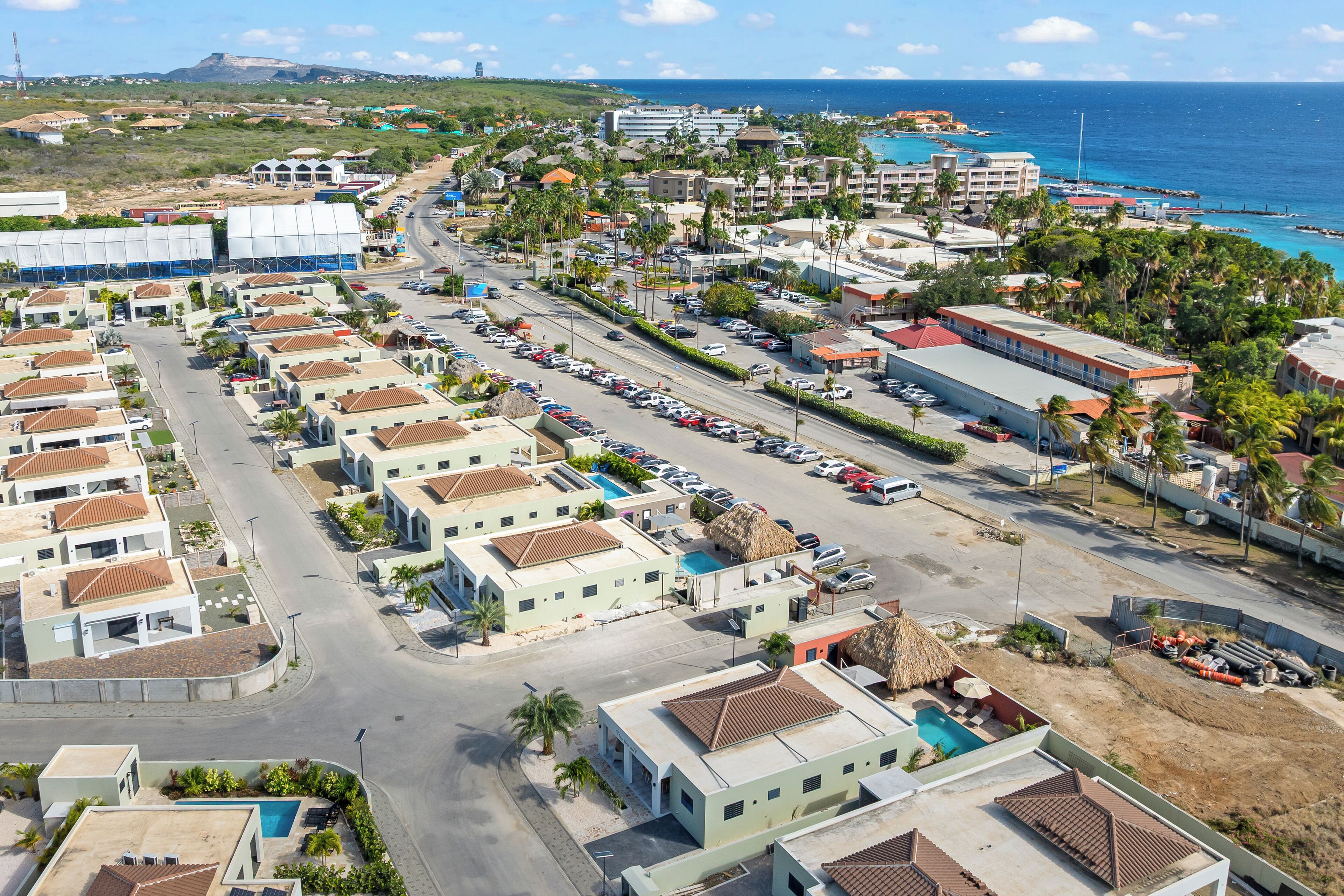 Un quartier résidentiel situé sur la côte, avec des immeubles à plusieurs étages, une rue principale et une plage en arrière-plan.