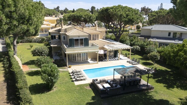 Uma casa grande com piscina, área de estar externa e um jardim bem cuidado.