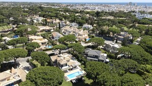Vista aérea de uma área residencial com casas, piscina e vegetação ao redor.