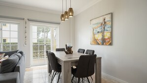A dining area with a wooden table, black chairs, and a hanging light fixture. - Mar e Golfe - Pool with golf view by HD (Vilamoura)