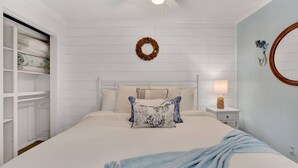 Une chambre à coucher comprenant un lit, une table de chevet, un miroir fixé au mur et une armoire.