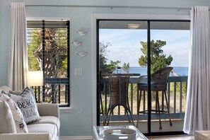 Una stanza con vista sul mare, un balcone con sedie e una finestra con una gabbietta.