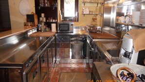 Una cucina professionale con elettrodomestici in acciaio inossidabile, un forno a microonde ed scaffali con bicchieri.