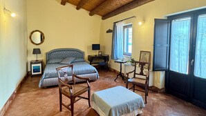 Una camera da letto accogliente con soffitto in legno, un letto, una scrivania e una finestra con tende.
