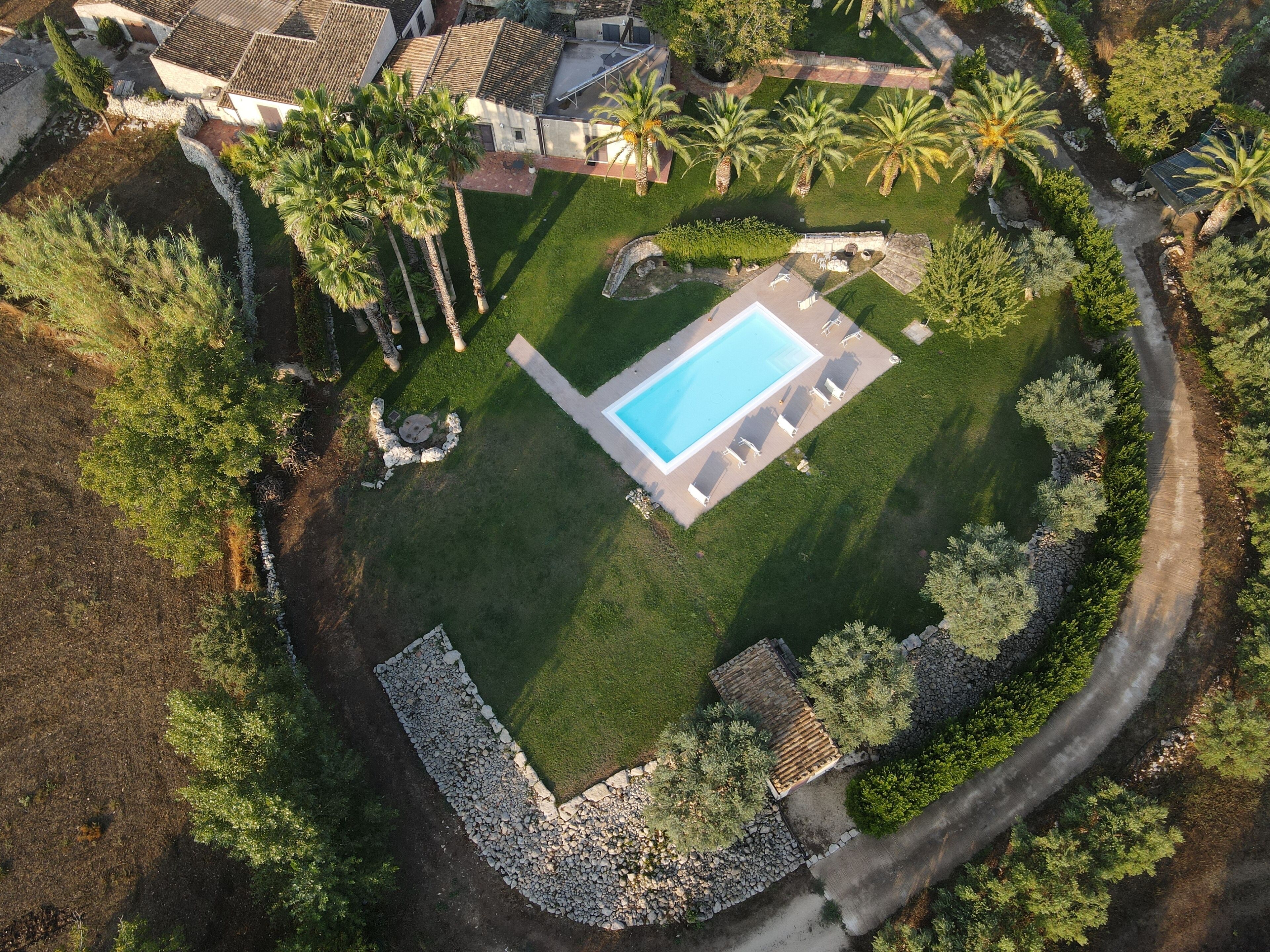 Luchtbeeld van een woonhuis met een zwembad, terras en omliggend groen.