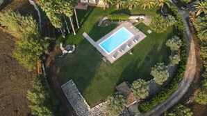 Vista aerea di una proprietà residenziale con piscina, patio e vegetazione circostante.