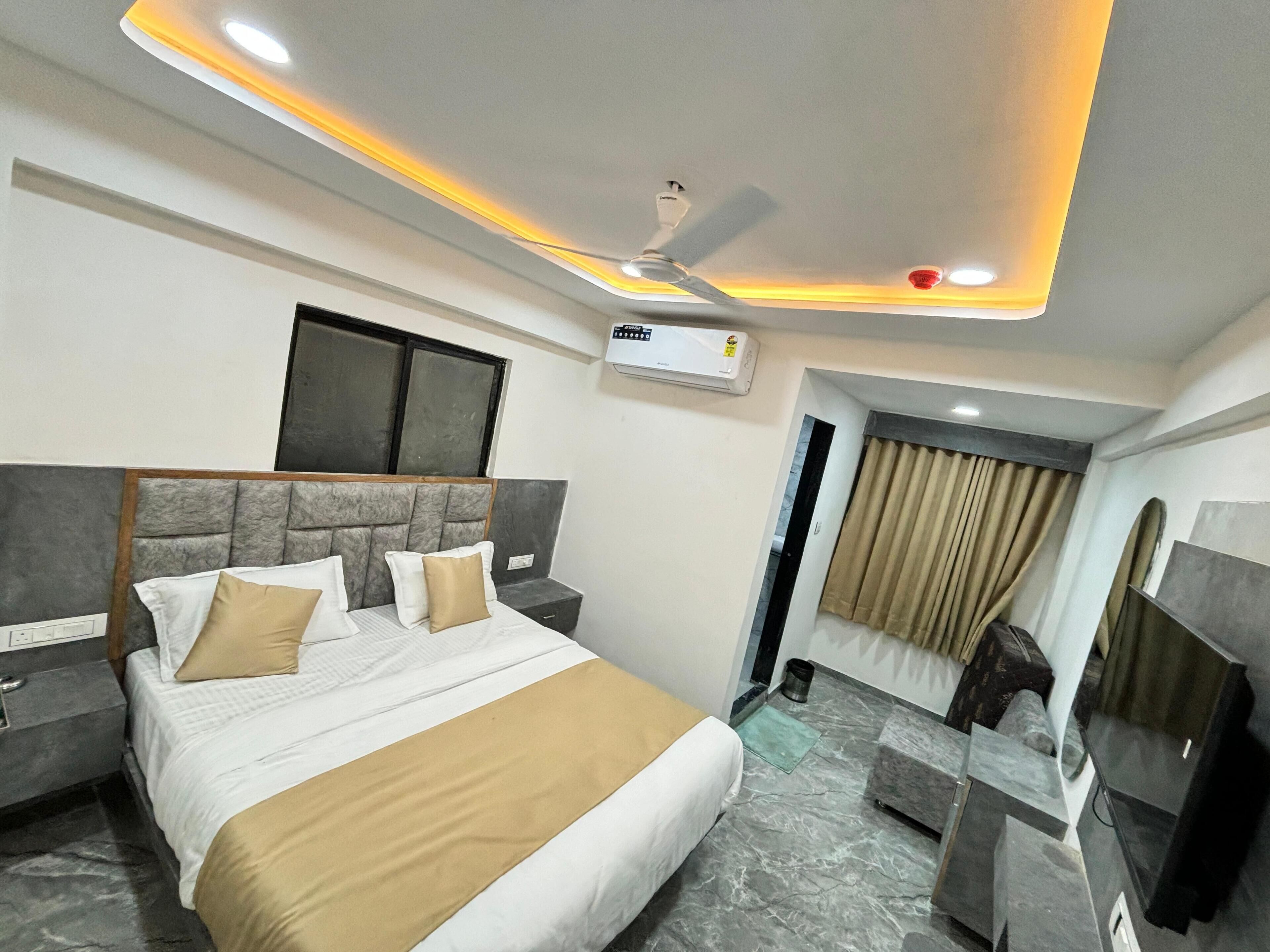 Una habitación de hotel moderna con una cama grande, un ventilador de techo, un equipo de aire acondicionado, un televisor y un piso de mármol.