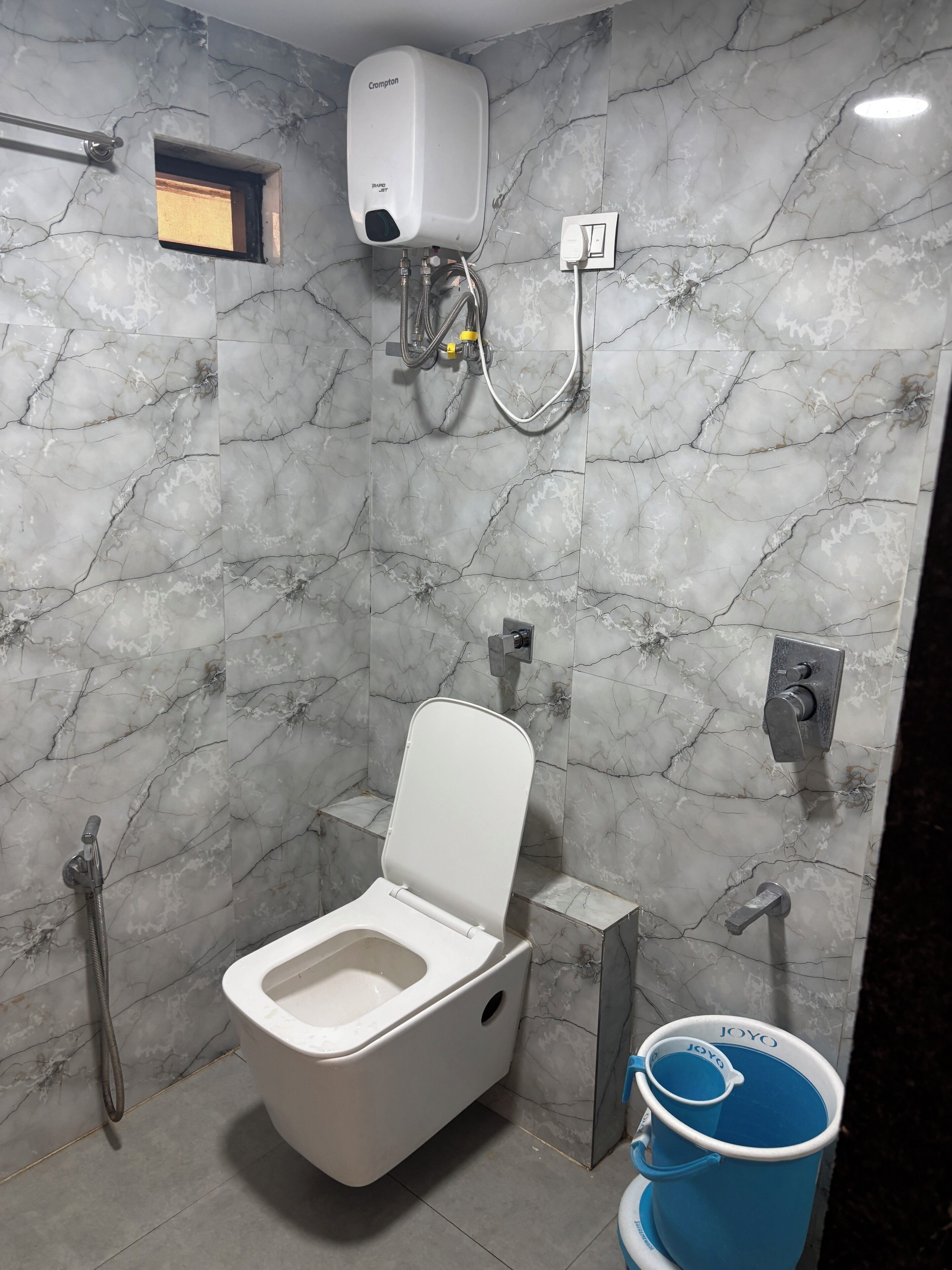 Une salle de bain équipée de toilettes, d’une douche et d’un sèche-mains fixé au mur.