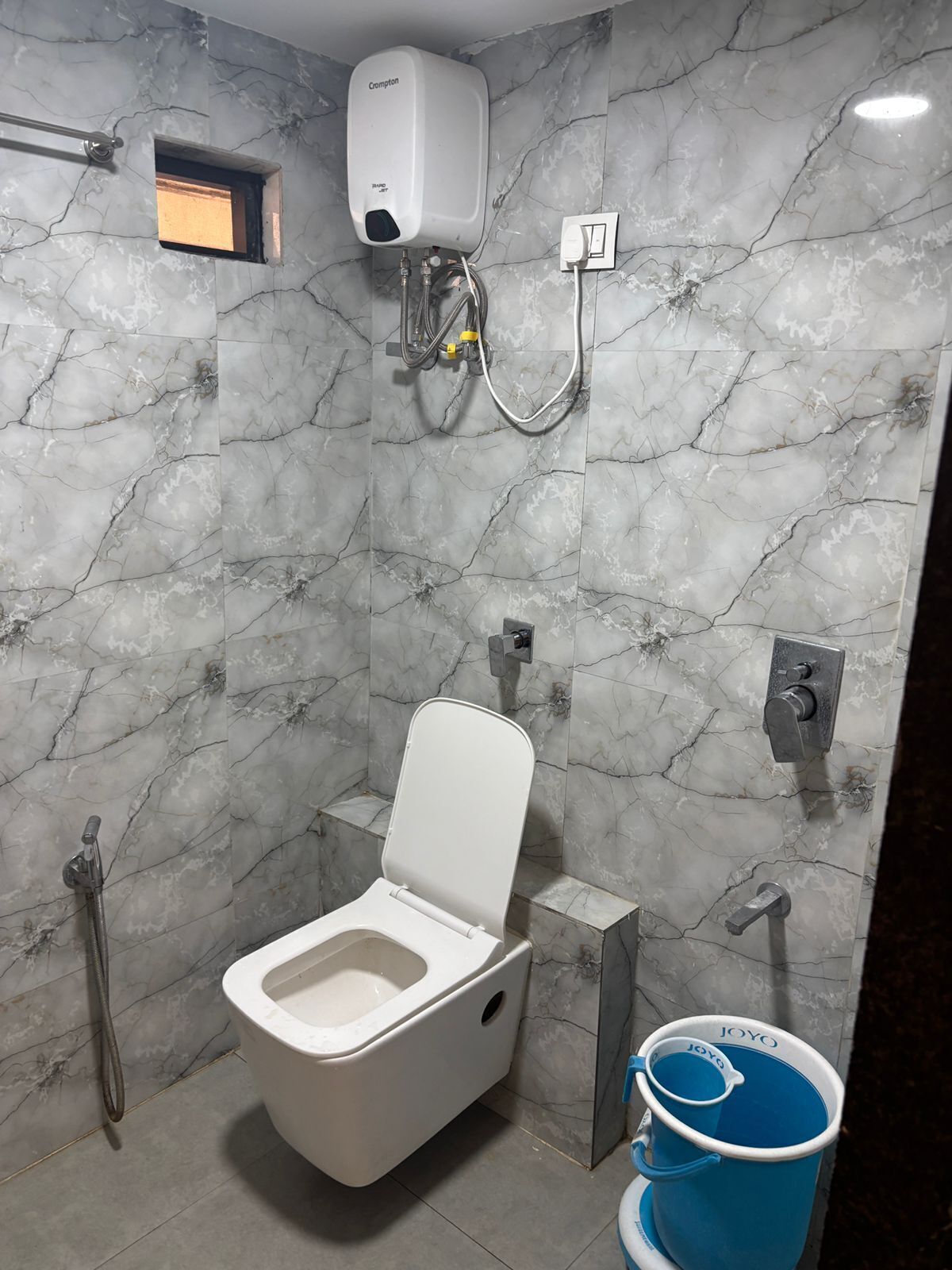 Une salle de bain équipée de toilettes, d’une douche et d’un chauffe-eau.