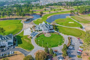 Vista aérea de un campo de golf con club house, zonas de estacionamiento y un lago.