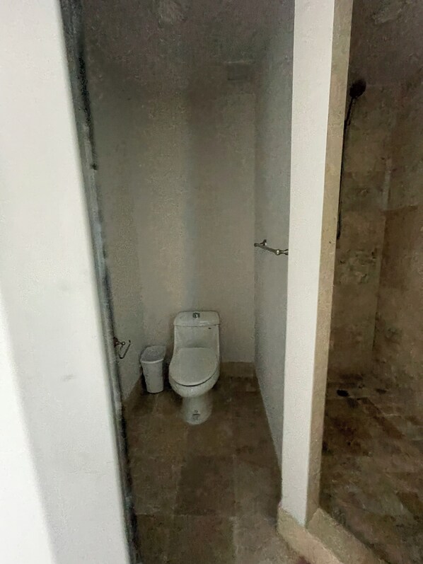 Ein kleines, schmales Badezimmer mit Toilette und Mülleimer.