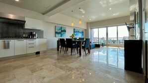 A modern kitchen with white cabinets, a granite countertop, and a dining area with a table and chairs. - Deck 12 Vallarta Residences (Puerto Vallarta)