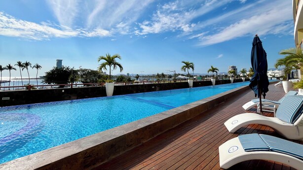 A pool area with lounge chairs and a view of the ocean. - Deck 12 Vallarta Residences (Puerto Vallarta)