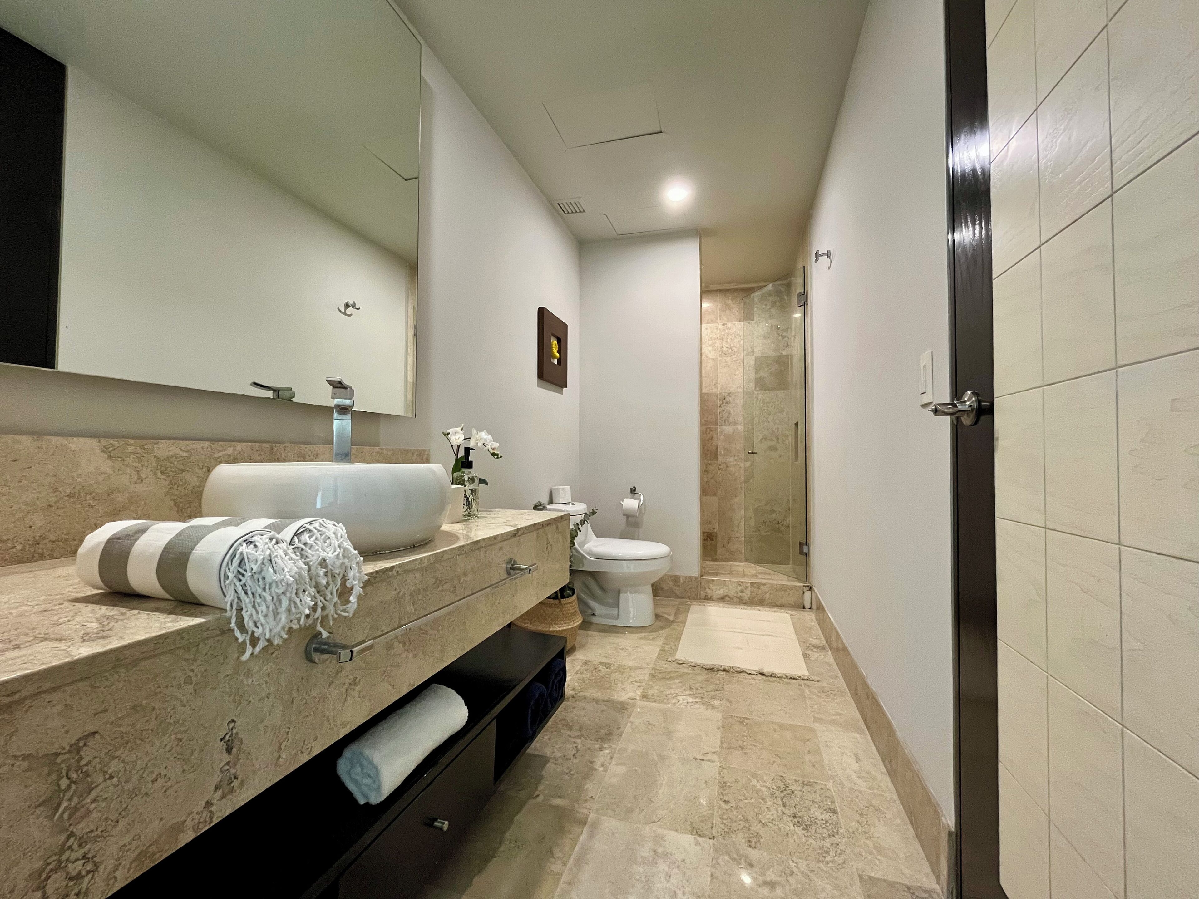 Un baño moderno con un lavamanos grande, espejo y retrete.