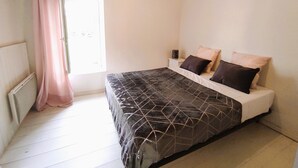 A bedroom with a bed, a nightstand, a window with curtains, and a radiator. - Ideal for a large family, authentic Landes house, pets welcome (Biscarrosse)