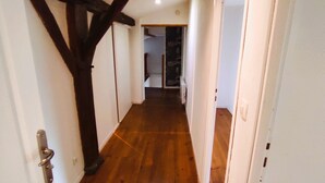 A narrow hallway with wooden flooring and white walls, leading to a room with a dark ceiling beam. - Ideal for a large family, authentic Landes house, pets welcome (Biscarrosse)