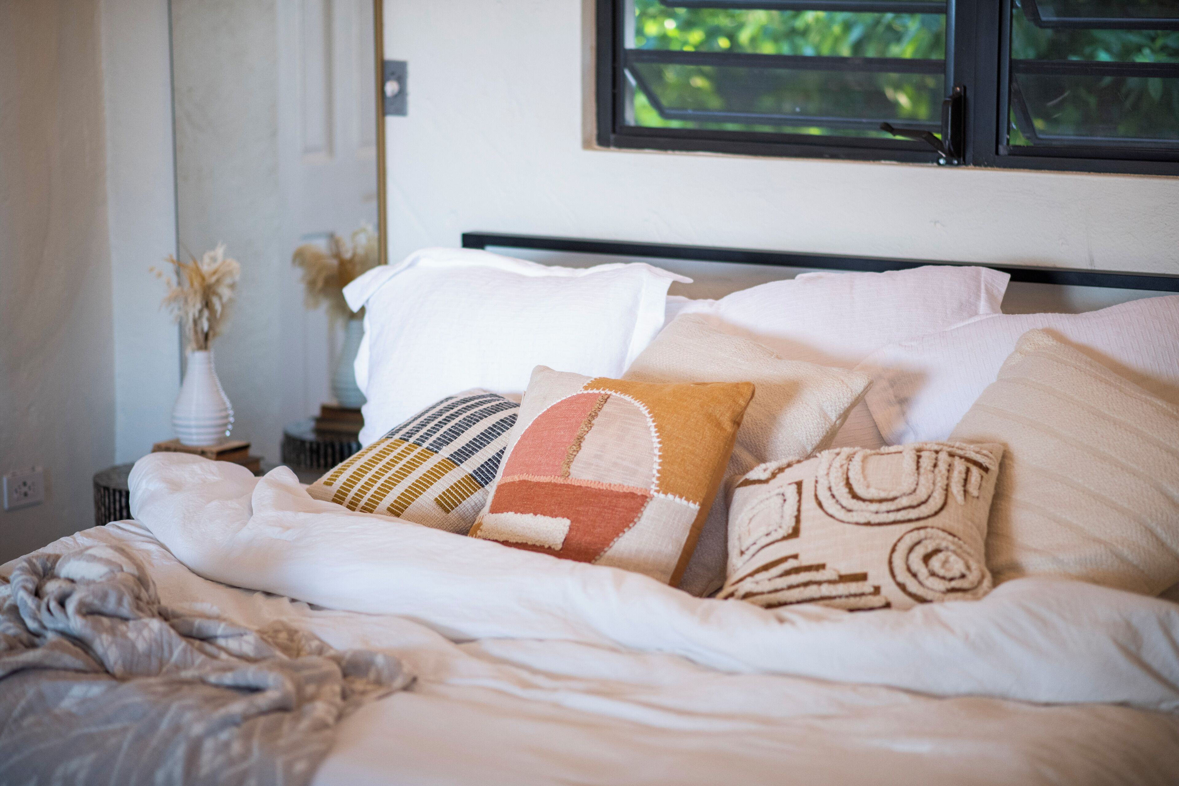 Un lit bien fait, avec plusieurs oreillers et une couverture blanche.