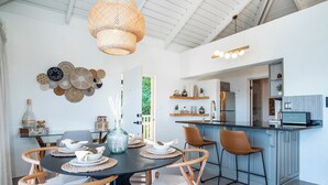 Una cocina moderna con una isla central, un comedor con una mesa redonda y sillas, y un colgador de luces.