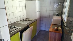 A compact kitchen with a gas stove, sink, and white refrigerator. - casa del torrent (Ota)
