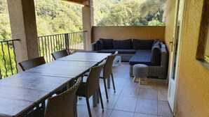 An outdoor patio with a dining table, chairs, a sofa, and a small ottoman. - casa del torrent (Ota)