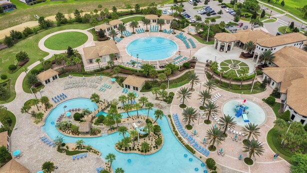 An aerial view of a resort with a central swimming pool, multiple lounge areas, and landscaped gardens. - Be our guest At Championsgate (Davenport)