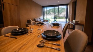 Un comedor con mesa de madera dispuesta para una comida, un sofá y vistas al exterior.