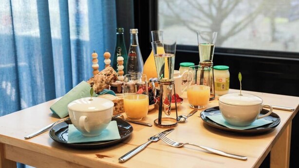 A breakfast table with a cup, saucer, juice, and a teapot. - Suite aux Anges N°1 (Antwerpen)